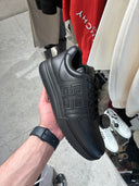 Sneakers épaisses en cuir noir avec monogramme embossé